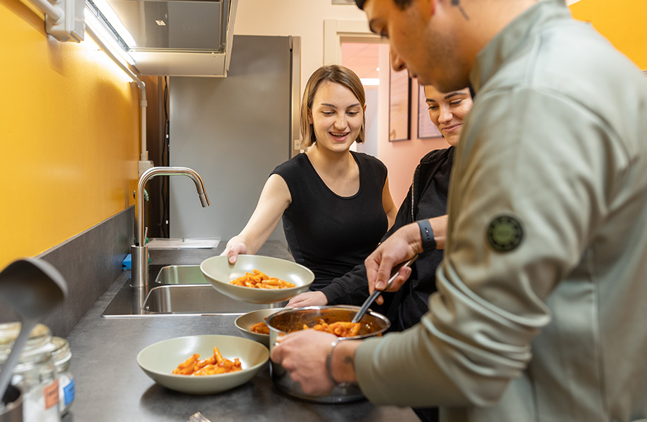 ragazzi che cucinano nella cucina condivisa di Lecco Hostel & Rooms